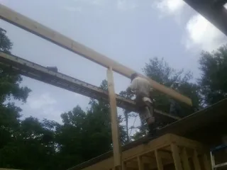 Carpenter setting a ridge beam over a new addition frame — Ice Dam Removal by Roofing Brothers in Toutle