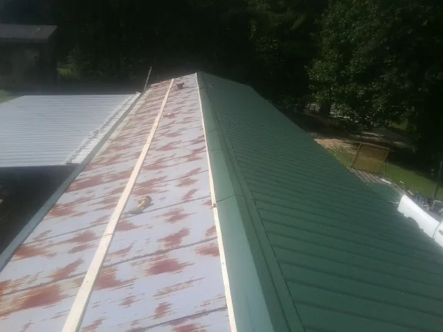 Old rusted panels beside newly installed green metal roofing — Wind Damage Roof Repair by Roofing Brothers in Toutle