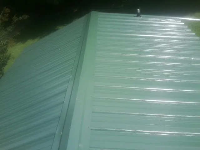 New green metal panels meeting at the ridge of a roof — Flat Roof Repair work by our crew in Toutle