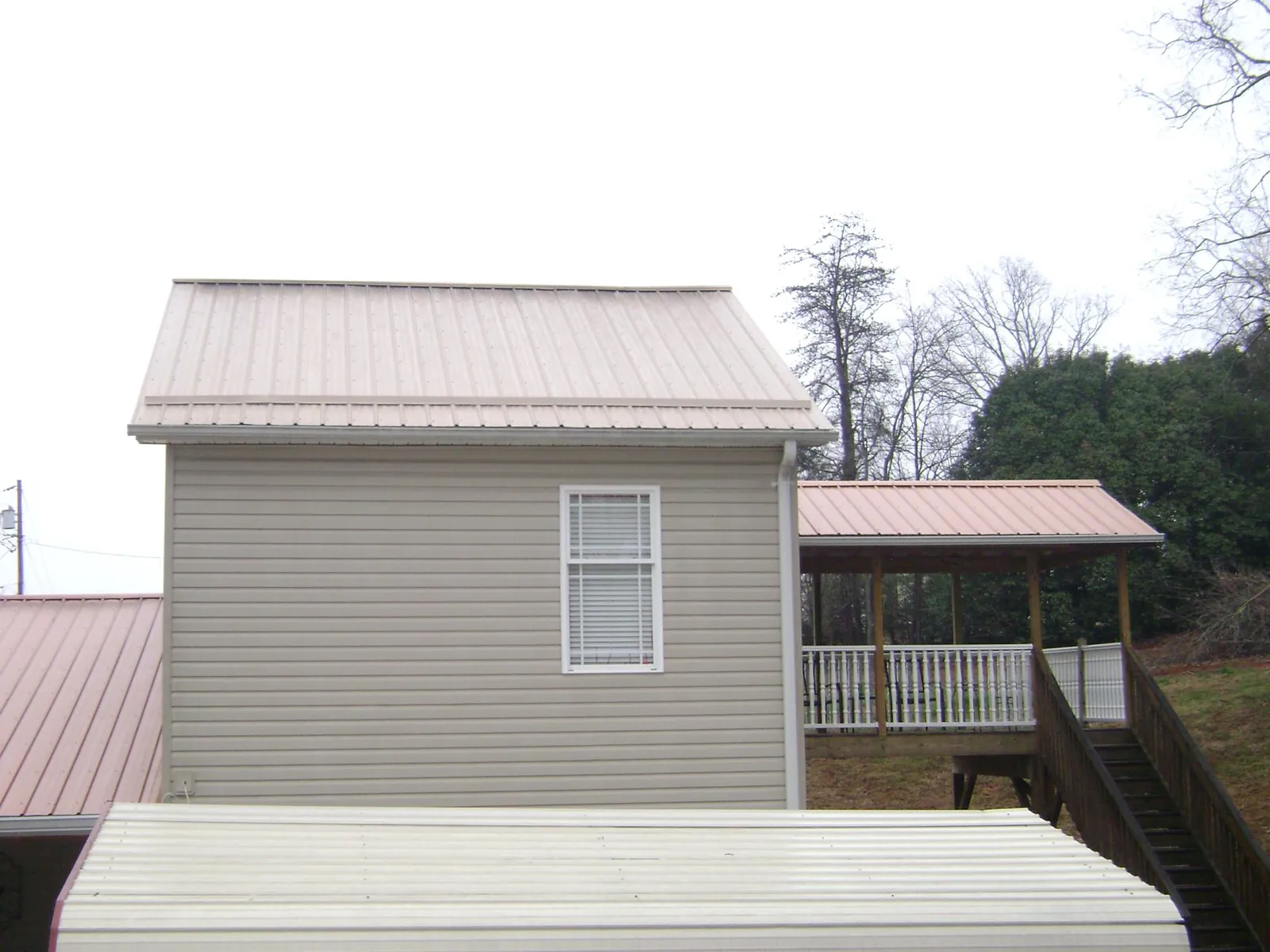 Tan metal roofs on a two story addition and attached porch, from a Roof Replacement job in Toutle