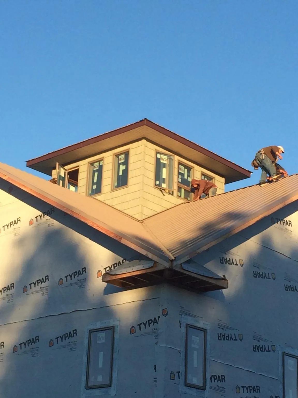 Roofers working around a rooftop cupola on a new metal roof at sunset — Roof Waterproofing in Toutle by Roofing Brothers